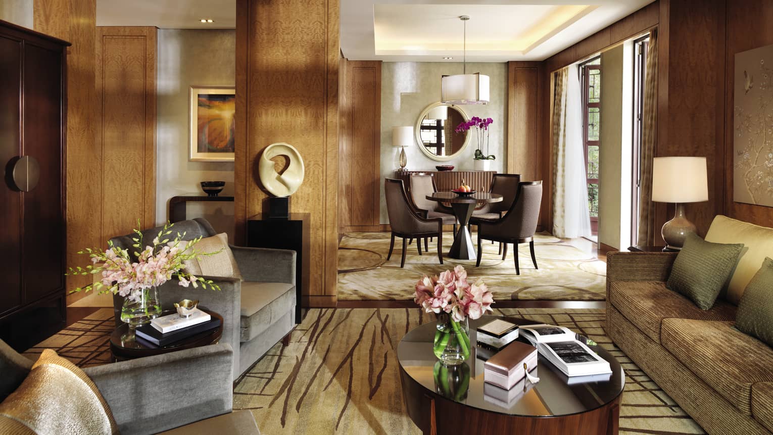 Lagoon Suite living room with modern sofas, chairs, table, art, by sunny dining room