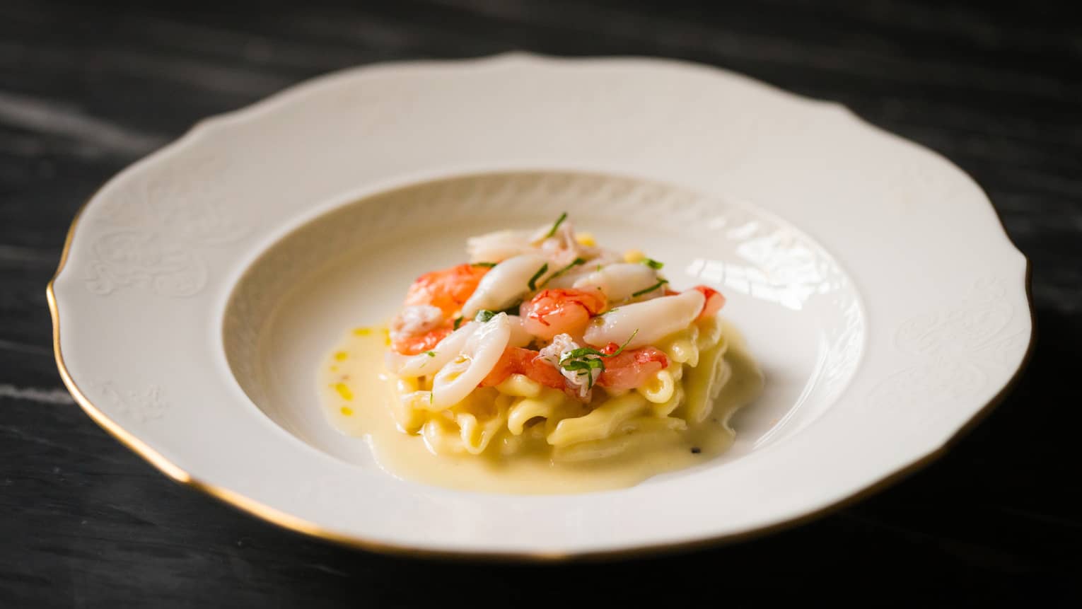 Seafood pasta in white dish on a dark table