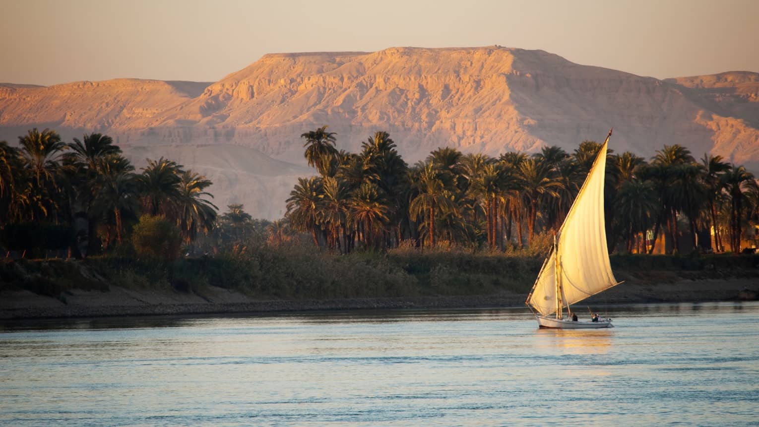Traditional felucca wooden sailboat on the Nile at sunset 