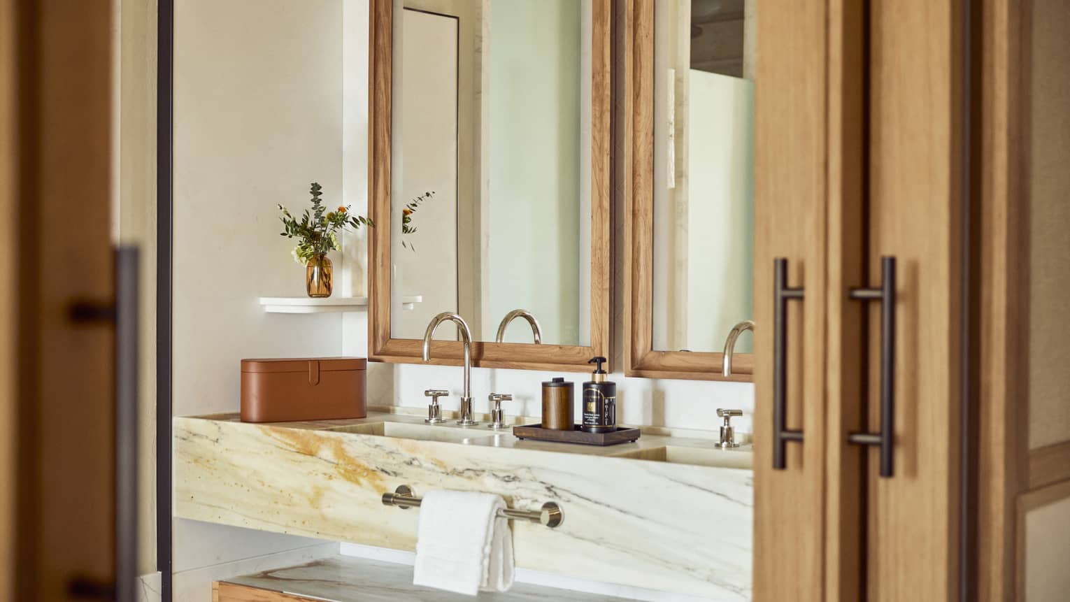 Wooden doors open to a modern marble vanity in bathroom
