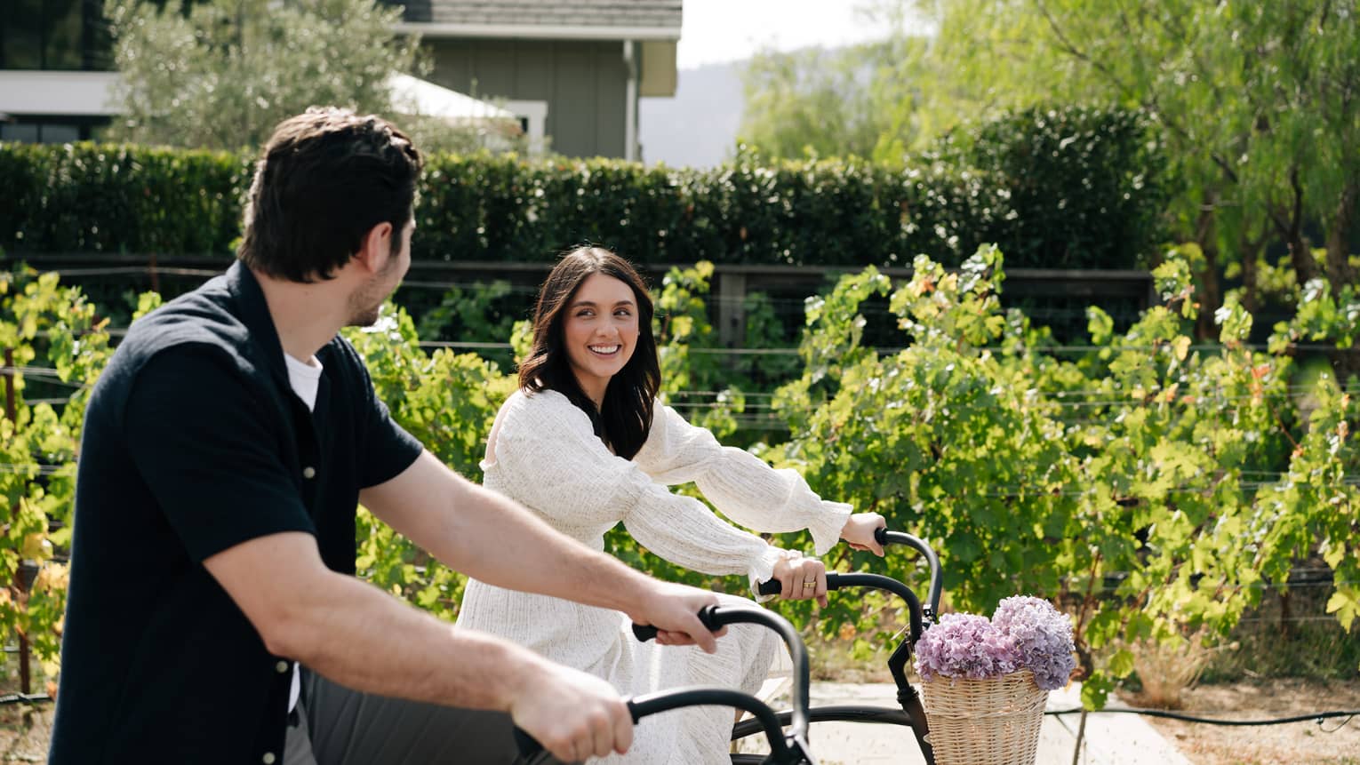 Man and woman riding bikes through the vineyard