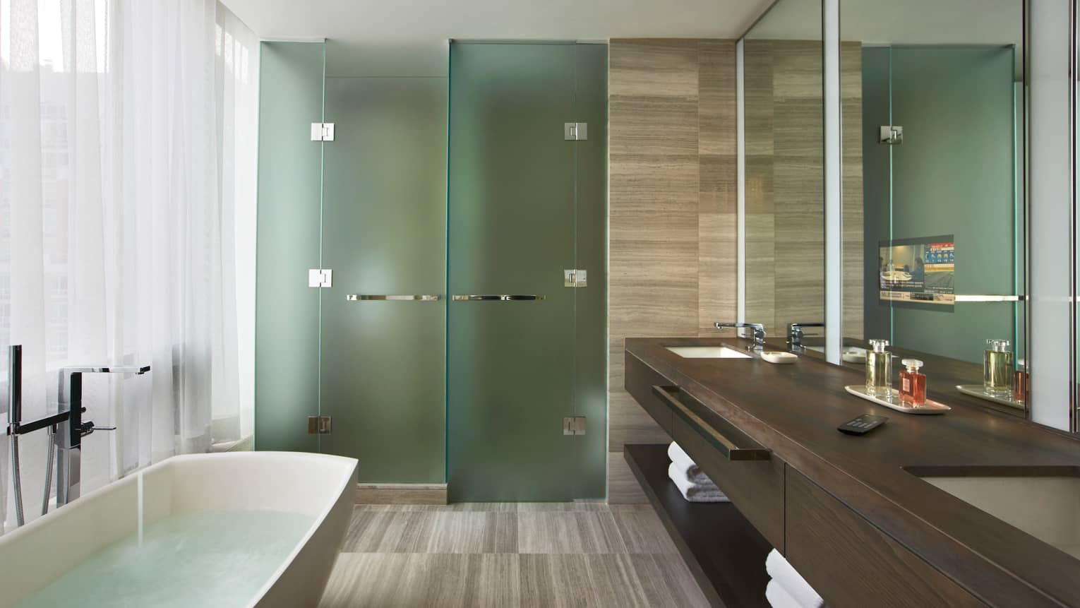 Granite bathroom with freestanding tub, glass rain shower and double wood vanity