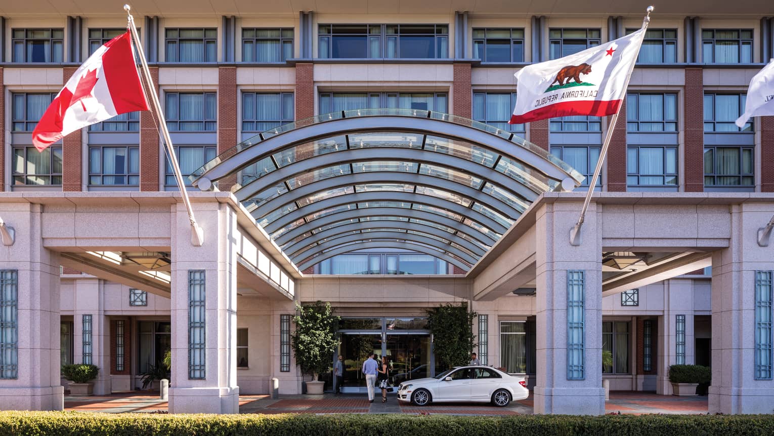 Arched glass, stone pillar entrance at Four Seasons Hotel Westlake Village, flags