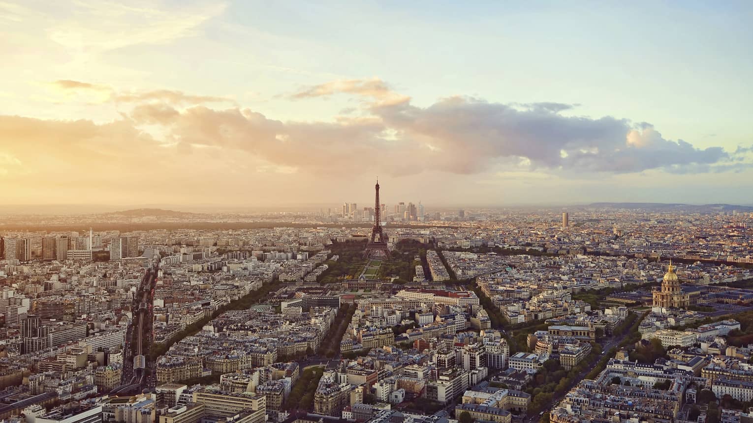 Sweeping city view of Paris rooftops, buildings, Eiffel tower at sunset