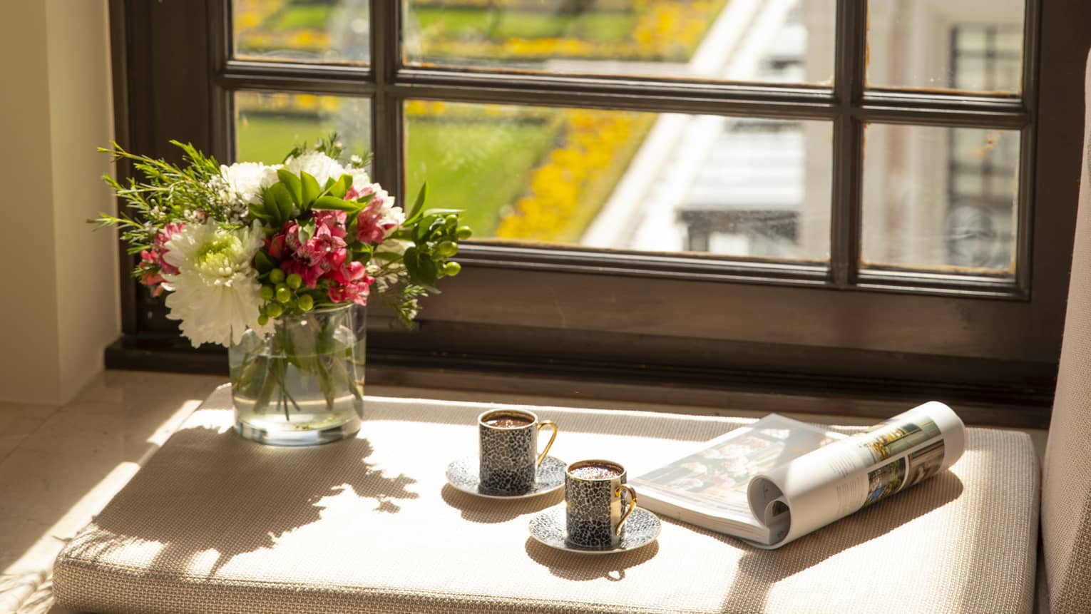 A tray of Turkish coffee, a newspaper and fresh flowers on the windowsill of a guest room, overlooking the city