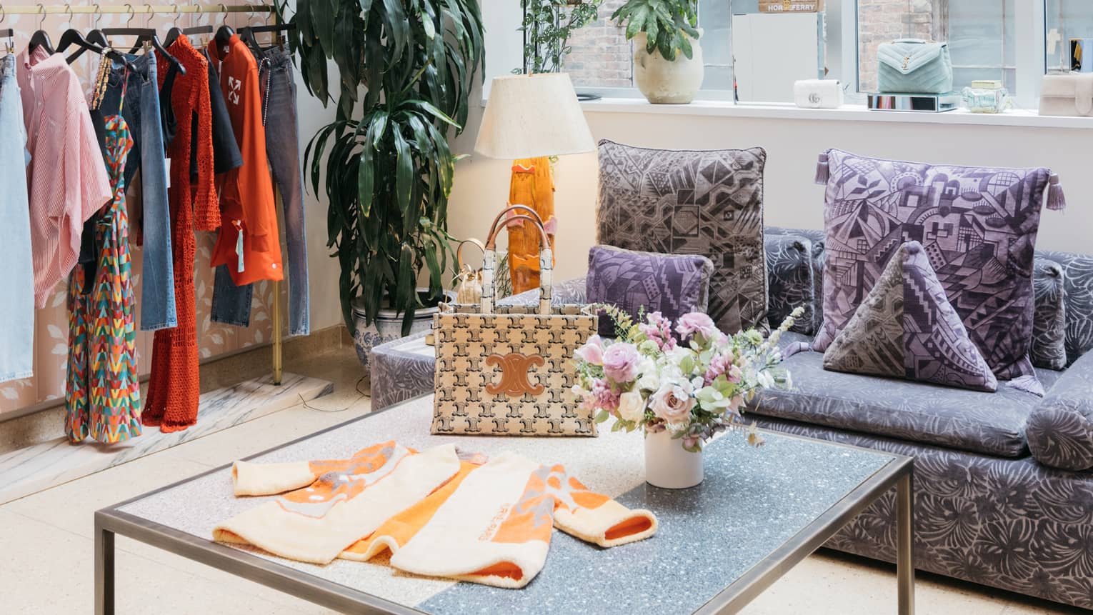 Clothes on a table and hanging near large windows.