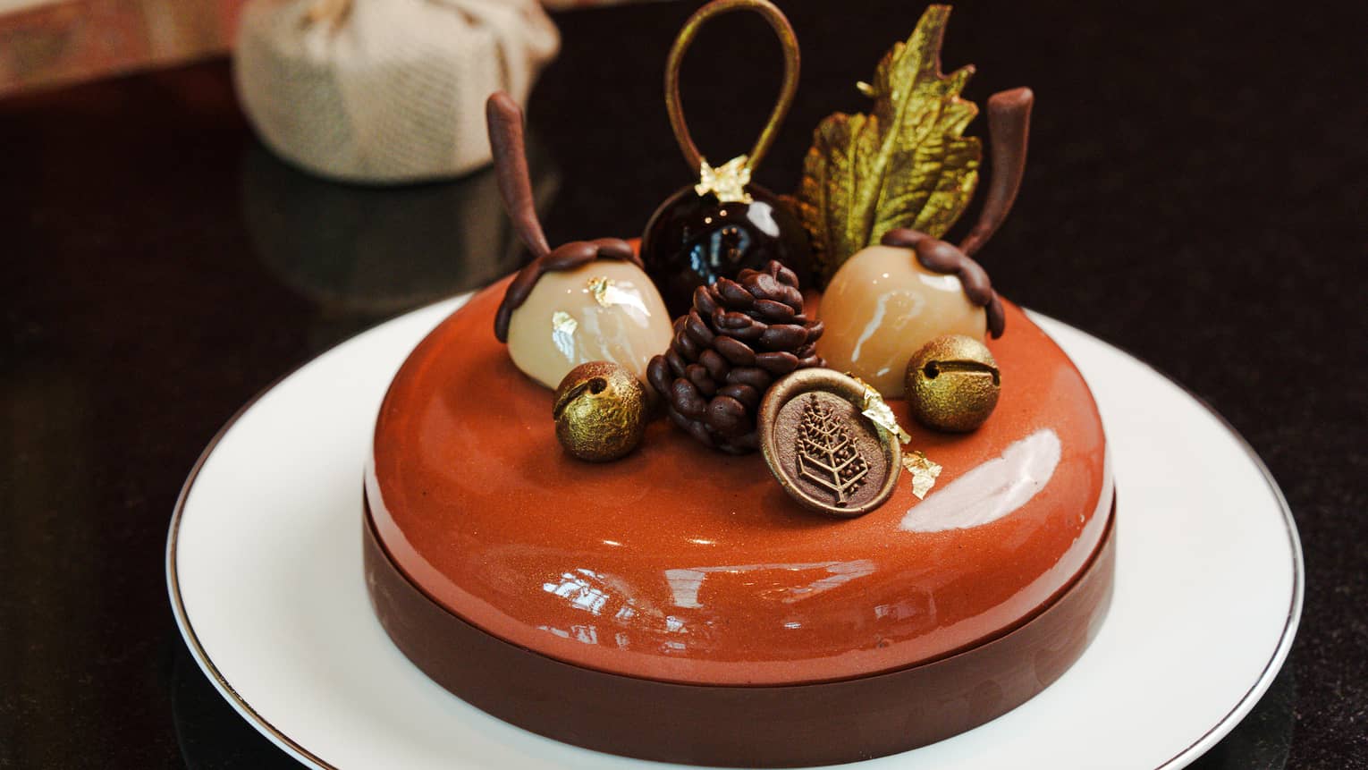 Festive cake topped with chocolate ganache and edible acorns, pine cones and bells