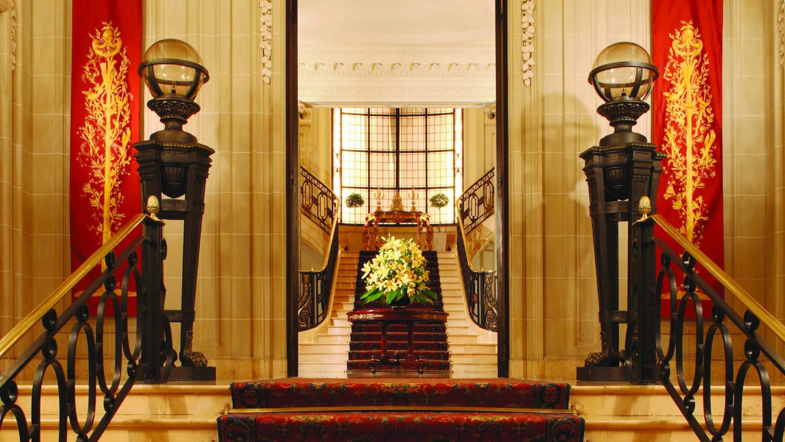 Intricate ceiling mold and a red carpet line the entrance to La Mansion