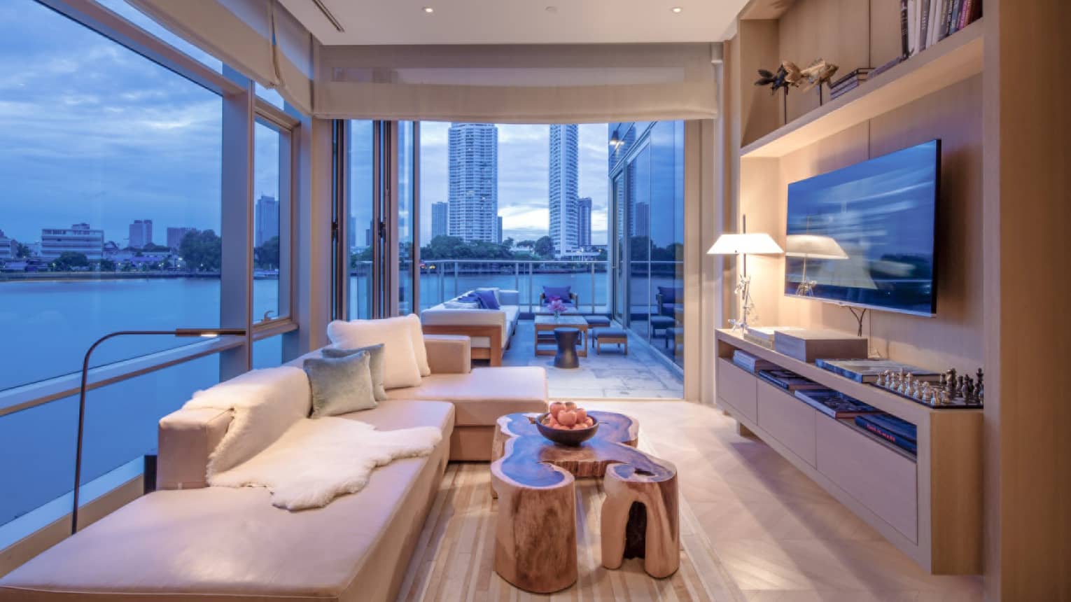 Living room with couch, coffee table and floor-to-ceiling windows with water and city view.