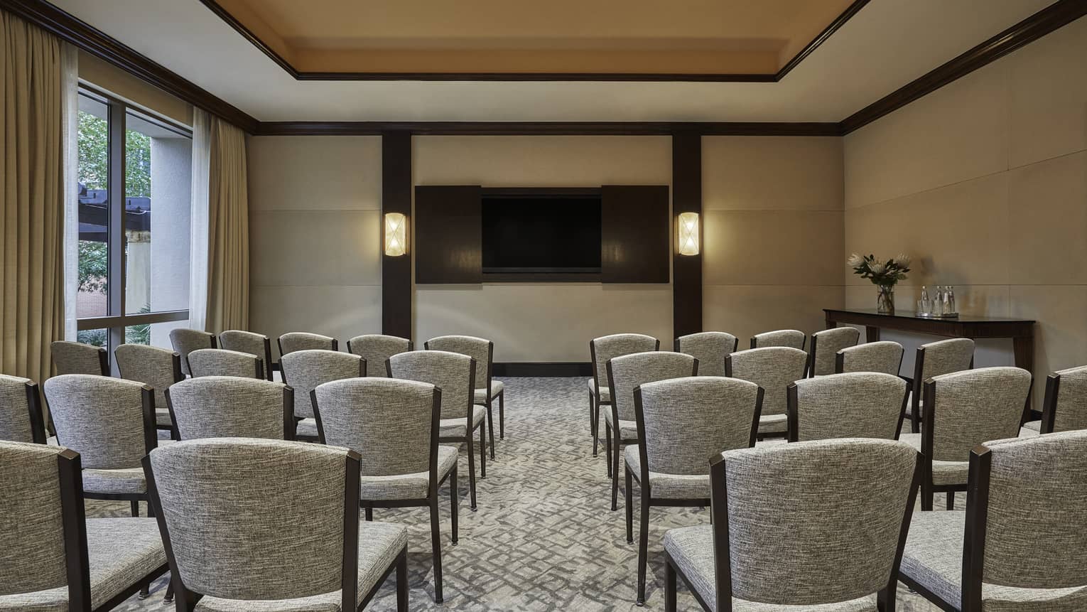 Rows of meeting chairs facing screen in bright Waterloo room