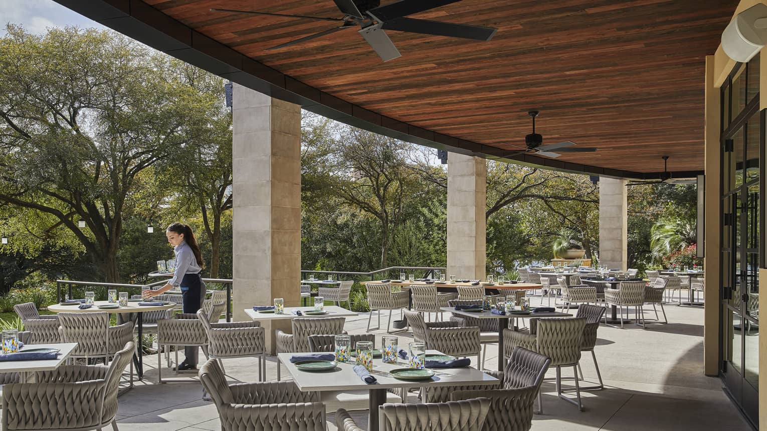 A waitress arranges place-settings on the shaded outdoor dining terrace at Ciclo.