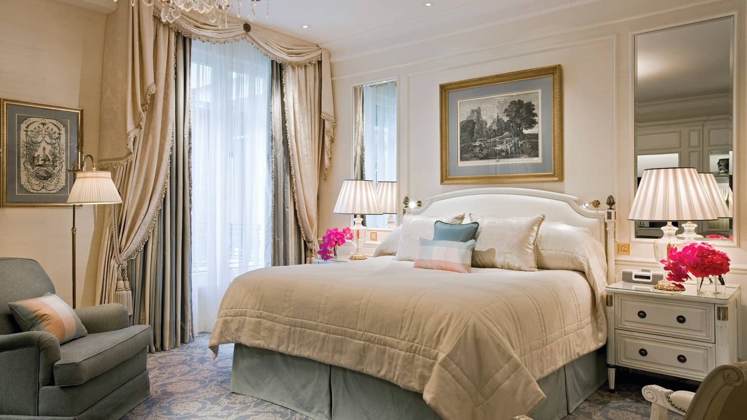 Hotel suite bed with silk pillows, flanked by mirrors, lamps, elegant curtains over windows