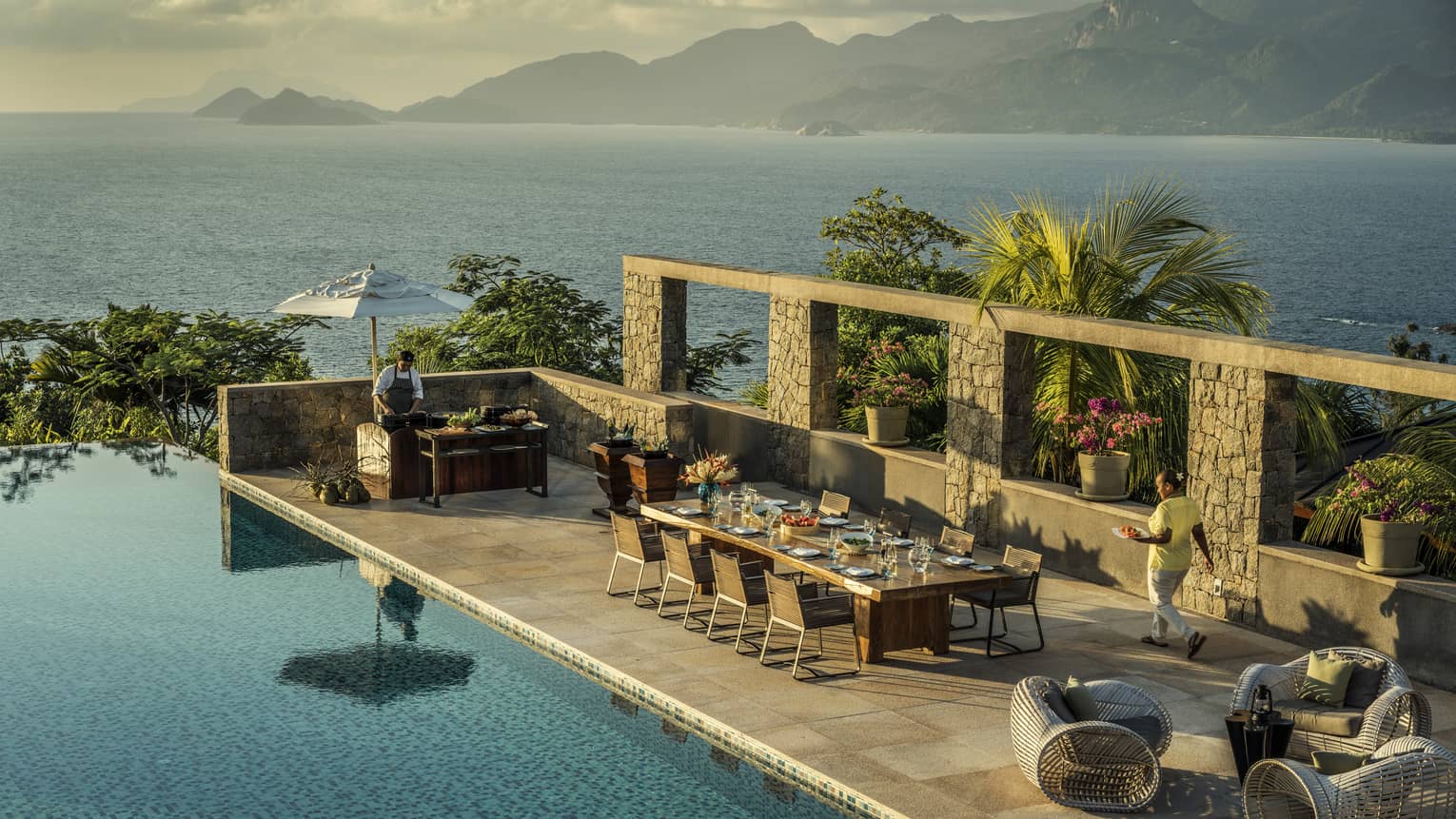 Aerial view of Four-Bedroom Residence Villa private deck with 8-person dining table beside pool, ocean view