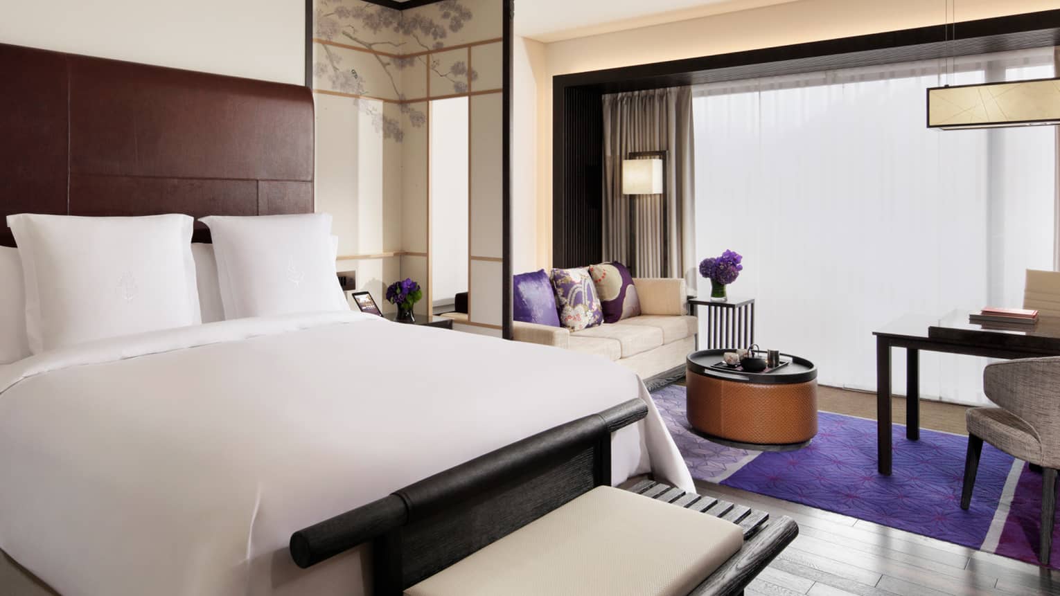 Premier Room with white bed, bench and loveseat, bright purple pillows and rug