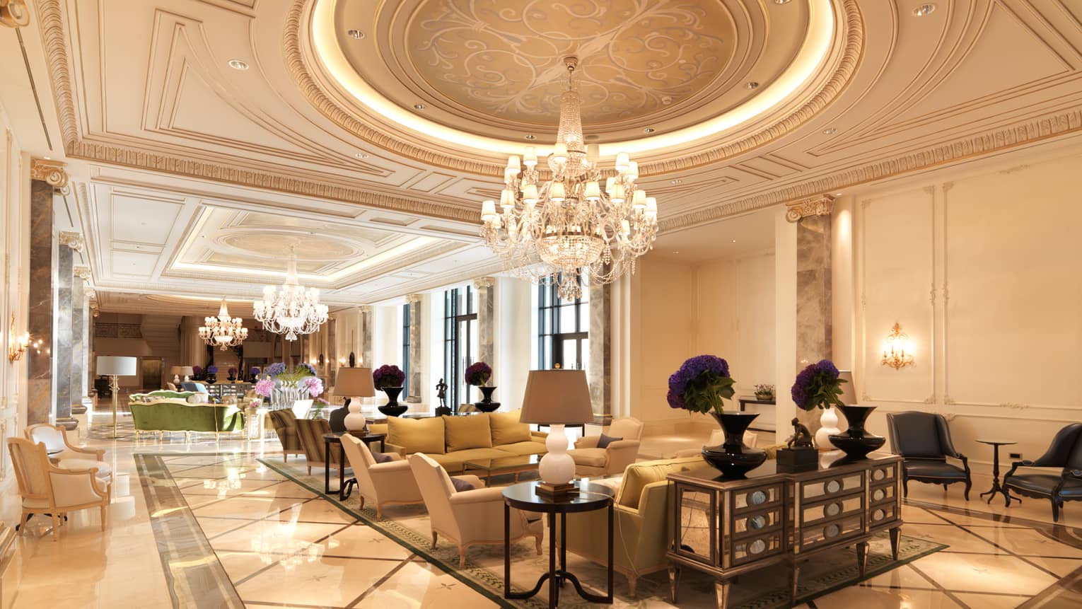 Baku hotel lobby with decorative Beaux-Arts ceiling, three large crystal chandeliers, clusters of armchairs below