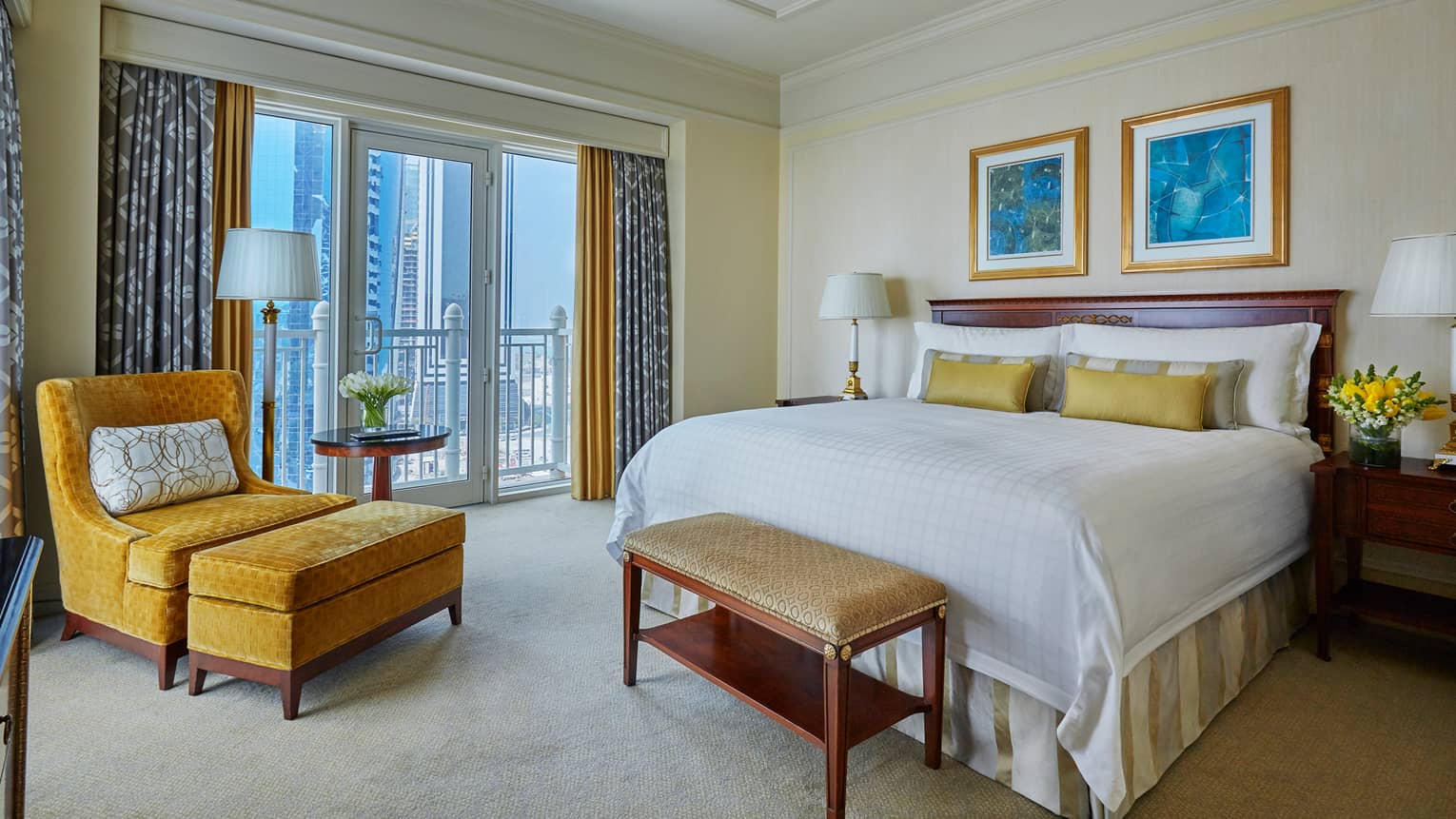 West Bay Three-Bedroom Suite bed with white linens, accent pillows, gold velvet chair by window