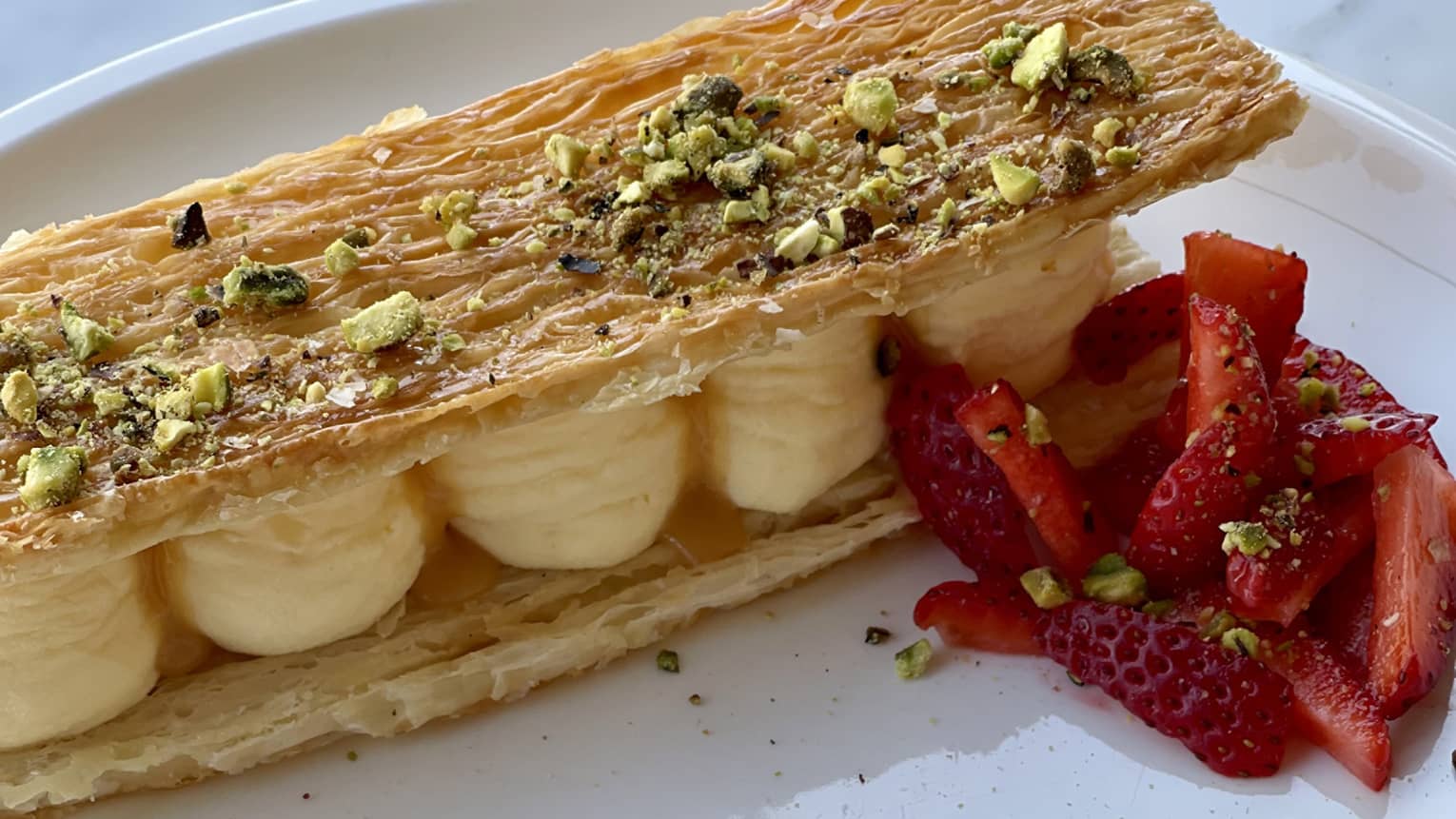 Sweet puff pastry filled with vanilla bean mousseline and garnished with strawberry and pistachio