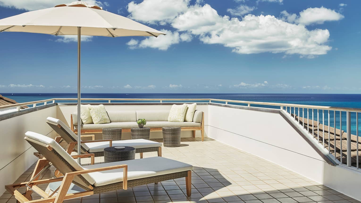White cushioned wicker patio furniture, umbrella on rooftop balcony