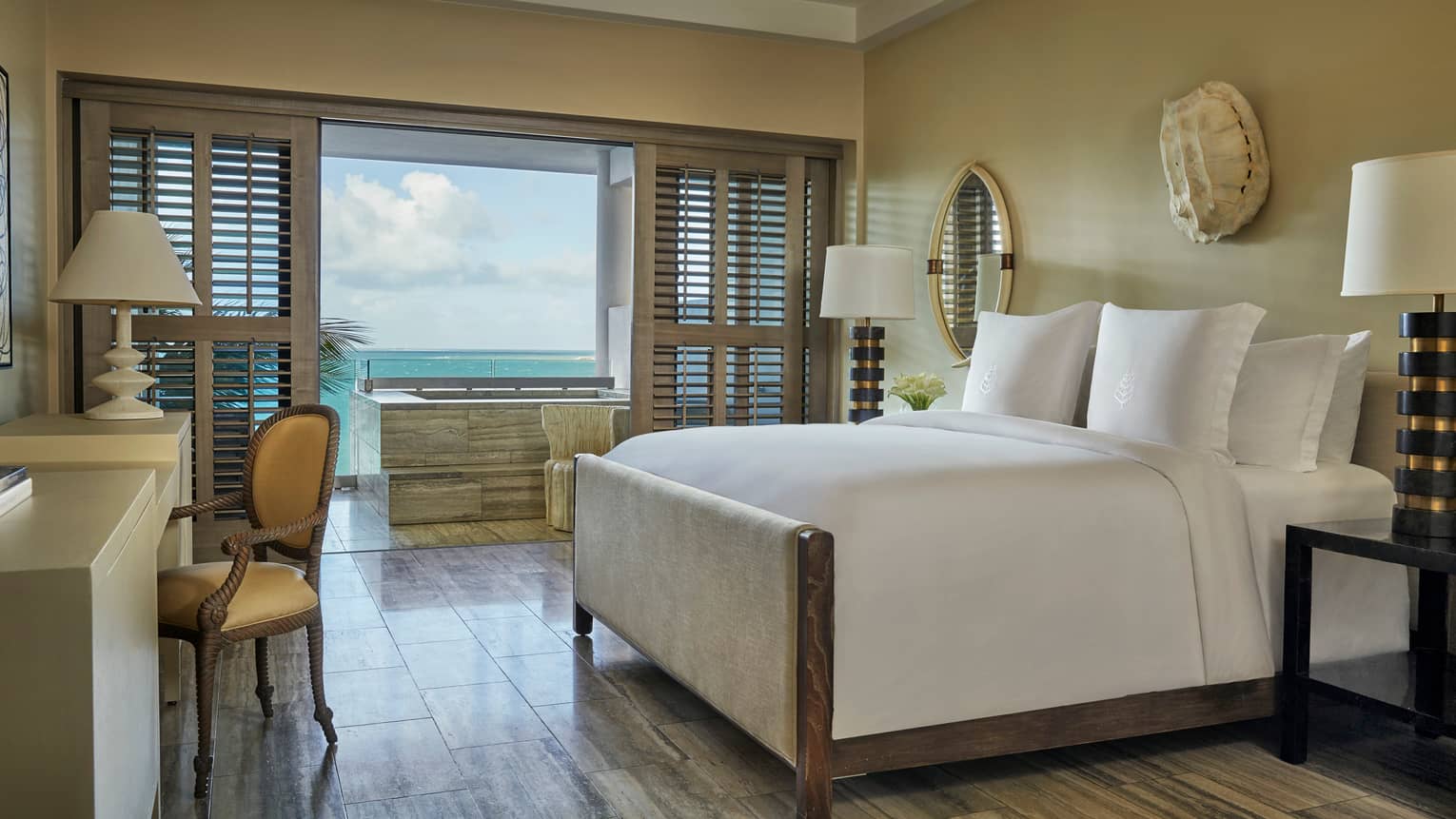 Ocean-View Studio Room bed, desk, bedside lamps, white wall sculpture, patio doors with wood shutters