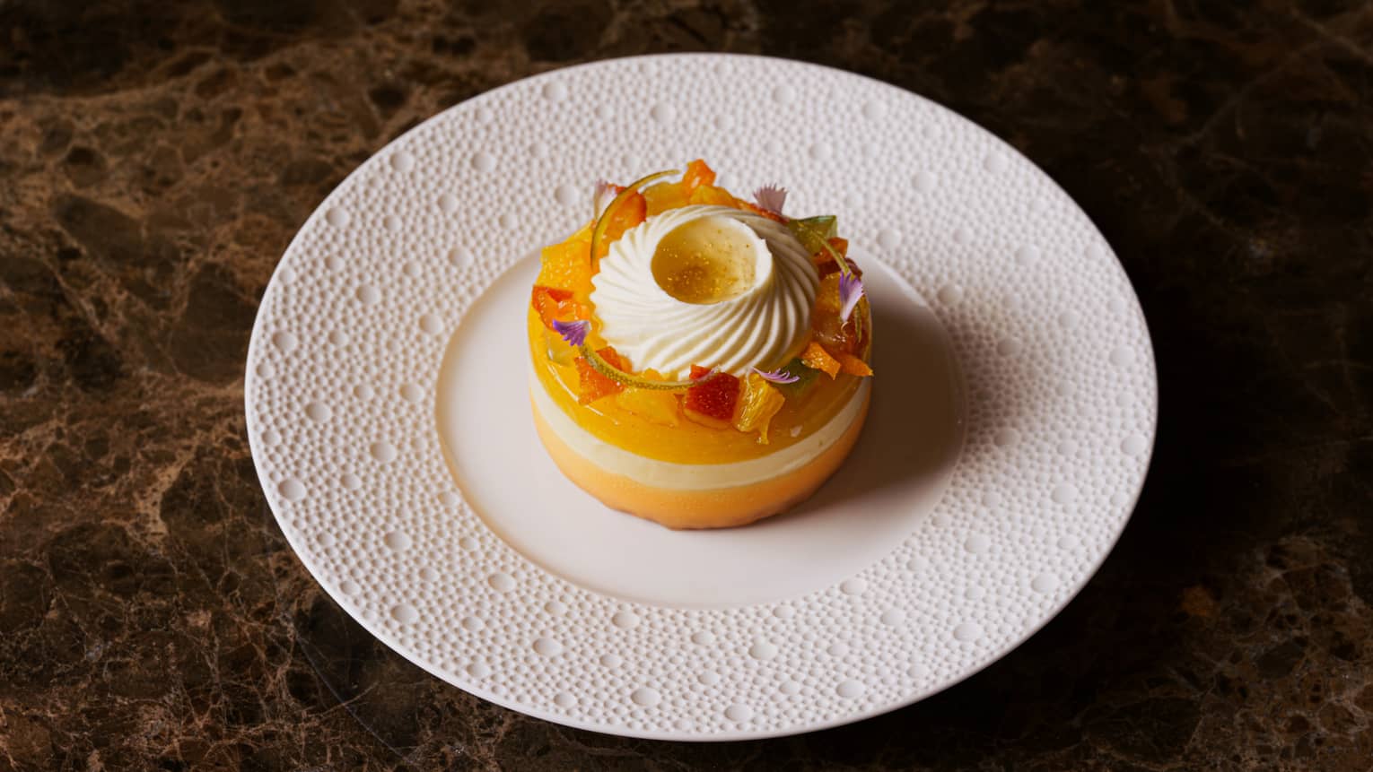 Round, yellow aliz�e cheesecake garnished with diced fruit