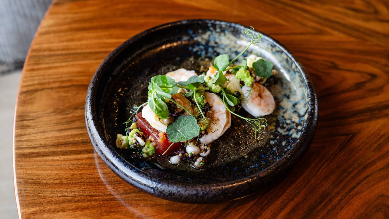 Shrimp dish plated in a black stoneware bowl