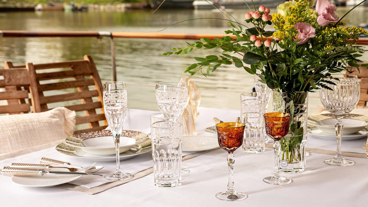 An outdoor table setting with a floral bouquet and a water view