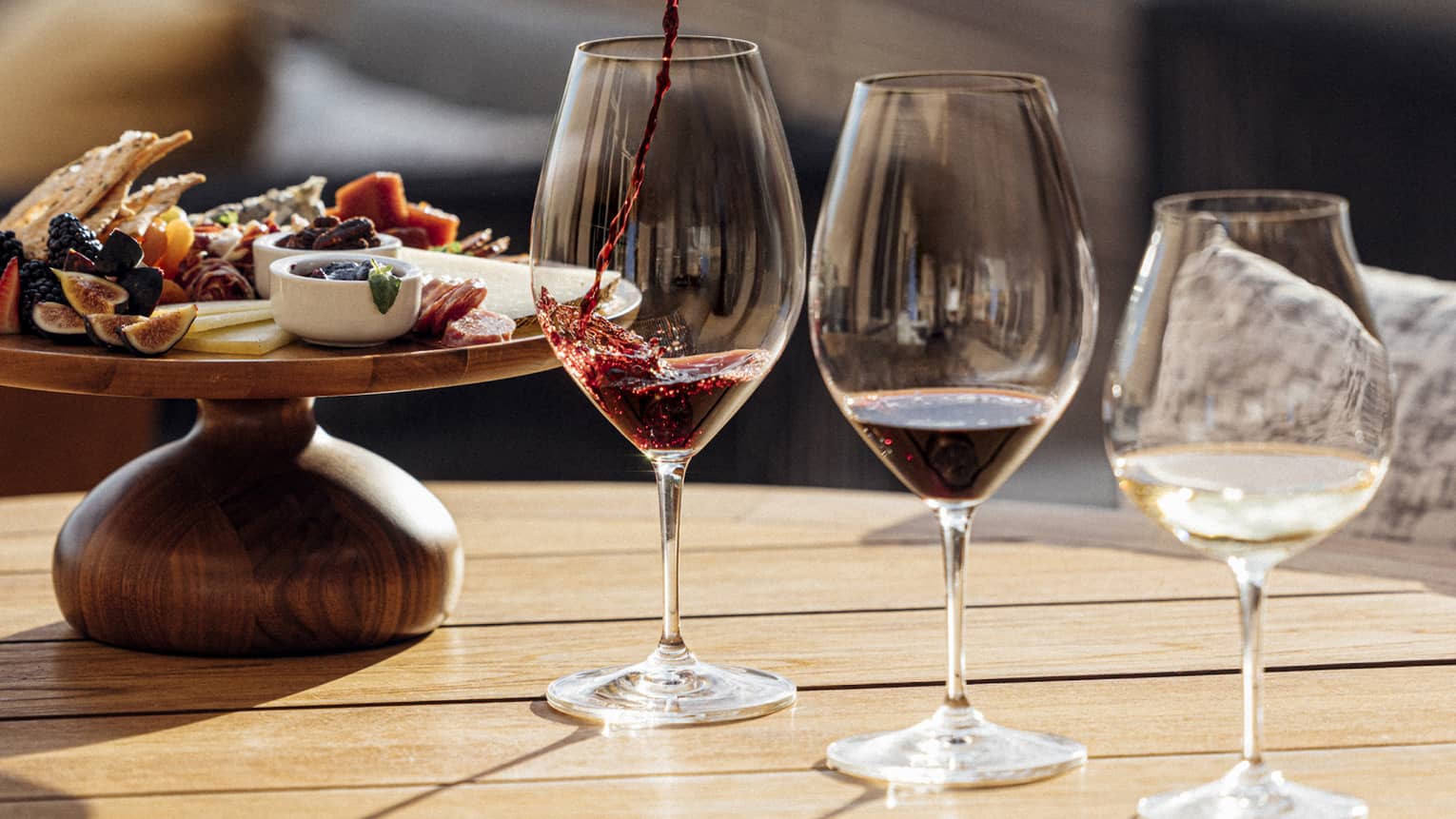 Three glasses of wine are poured next to a plate of charcuterie