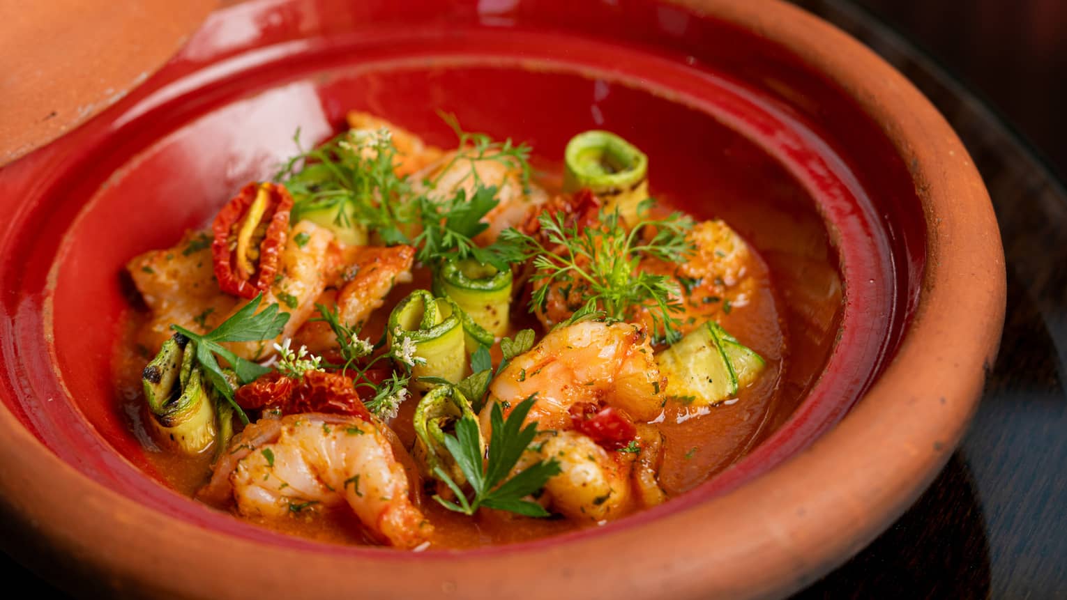 Moroccan Prawns Tajine with parsley in red clay bowl
