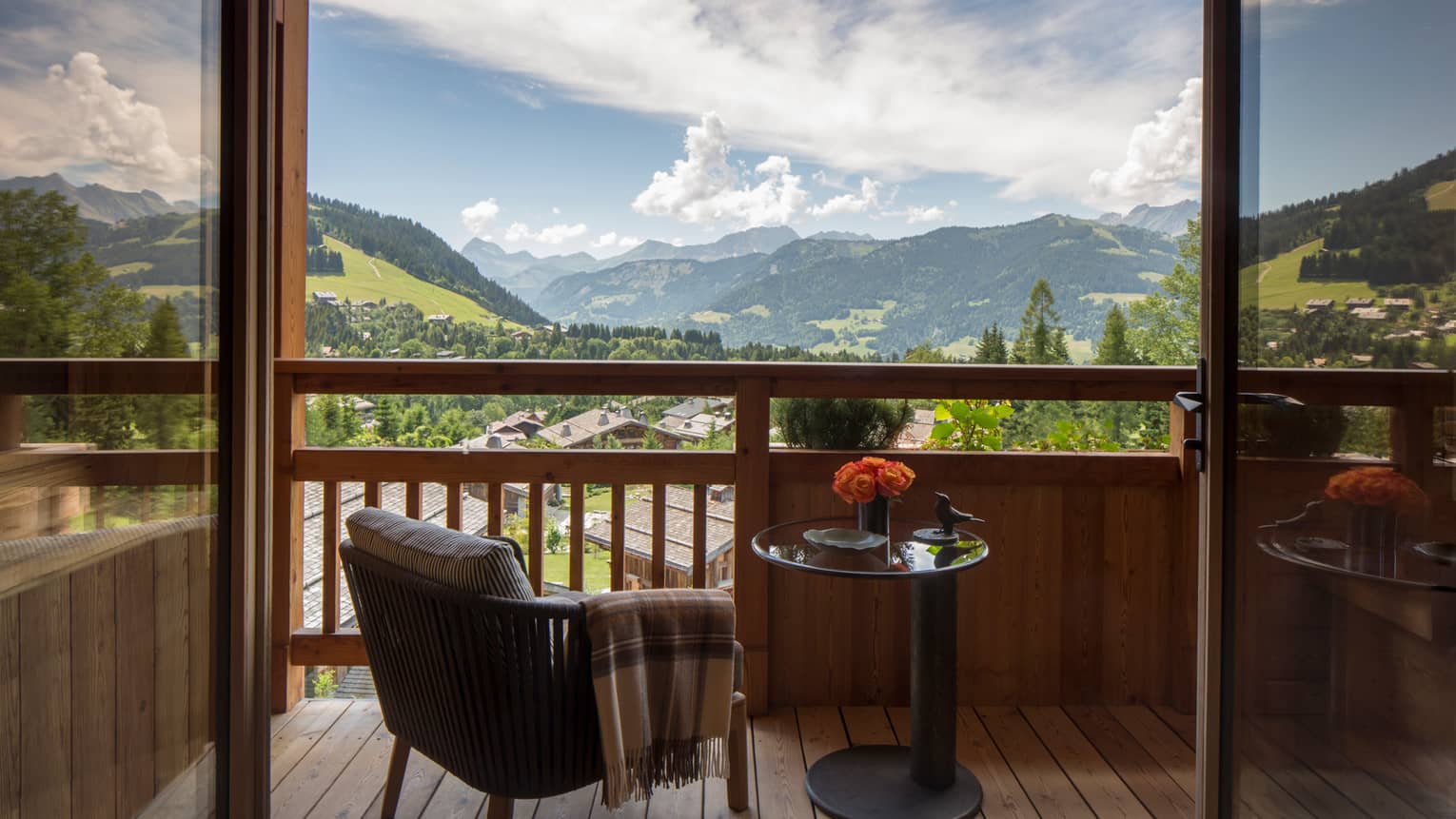 Suites des Alpes patio chair with blanket, table with flowers on balcony overlooking French Alps