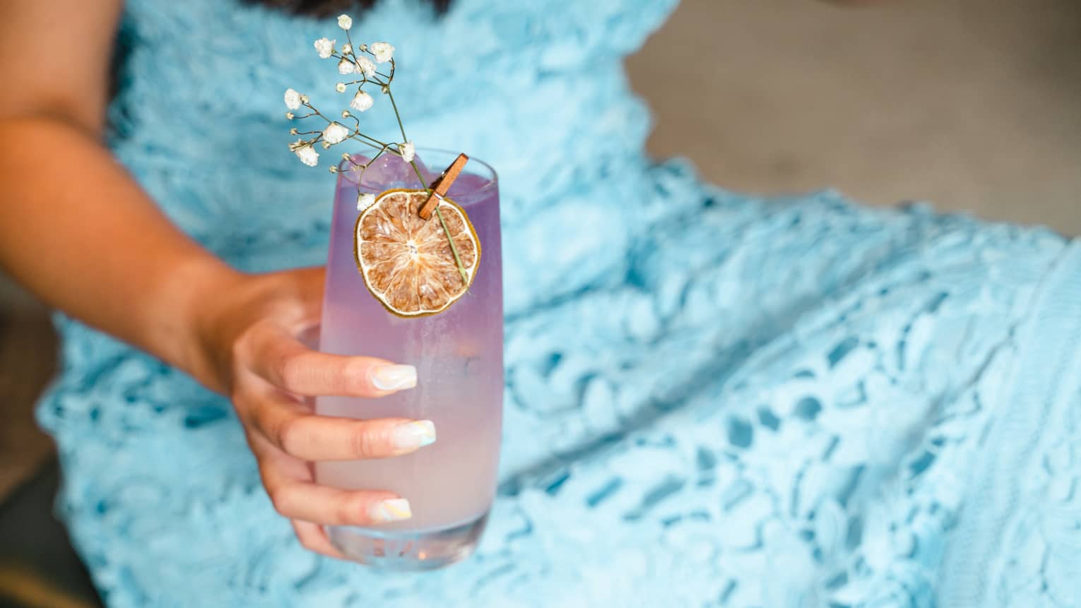 A purple and white cocktail with an orange wheel garnish.