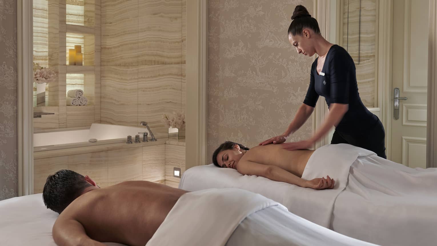 A four seasons staff massages a woman while her partner lies on a massage bet beside her at the four seasons george paris spa