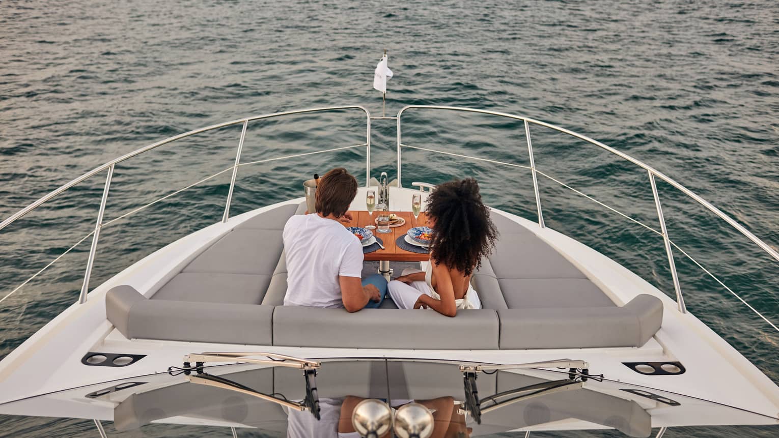 A man and woman eating food on the deck of a boat.
