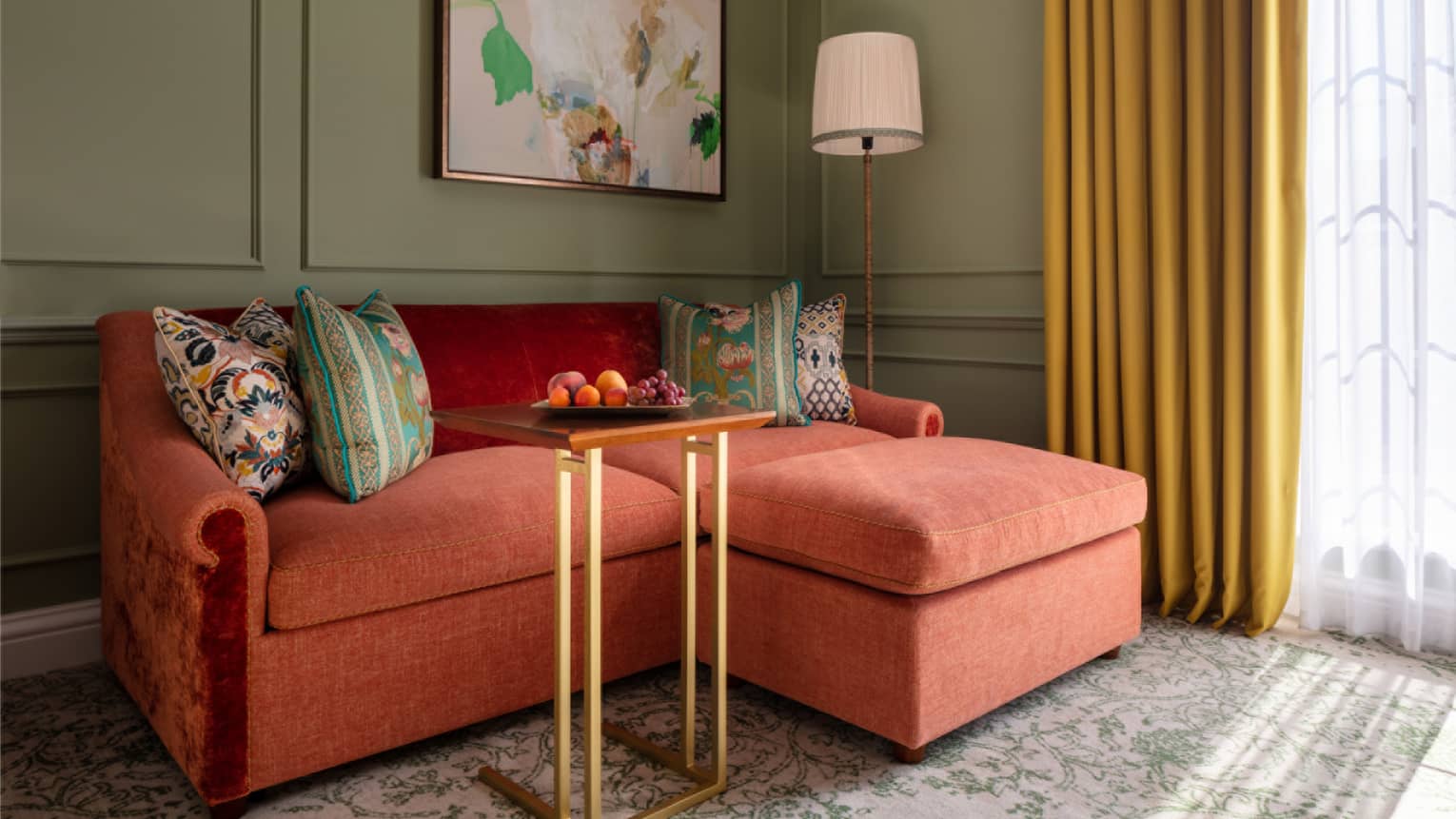 Red loveseat with patterned throw pillows, paisley carpeting, floor-to-ceiling window with yellow drapes