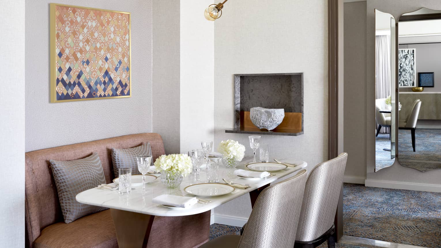 Dining table for four, with two silver chairs and a pink sofa