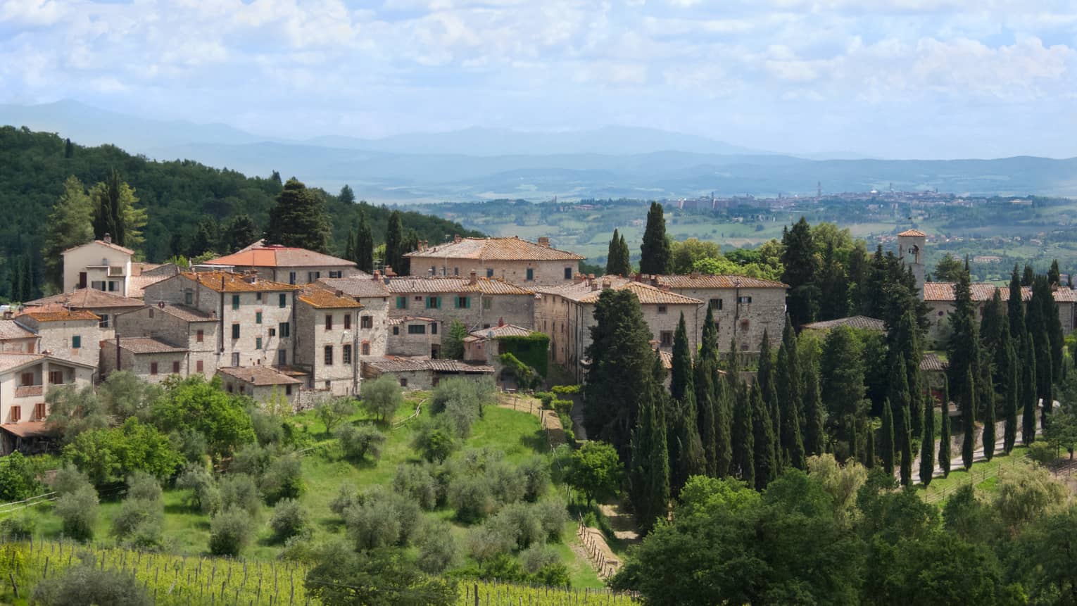 Tuscan countryside with historic stone building against rolling green hills