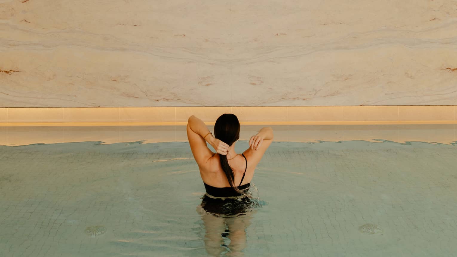 Person wearing a swimsuit and standing in the pool water.