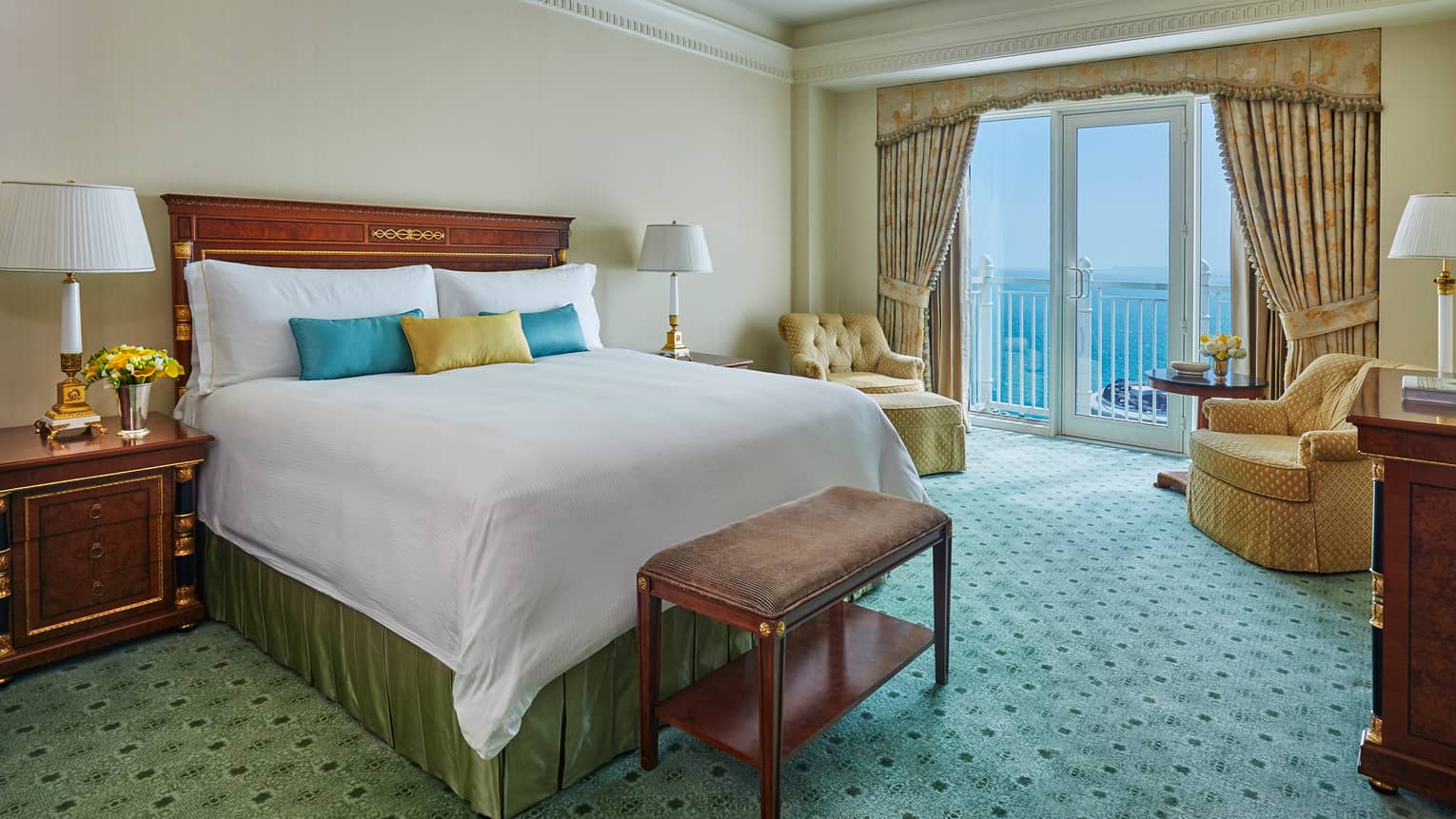 West Bay Two-Bedroom Suite bed with blue and yellow accent pillows, green carpet, glass patio doors