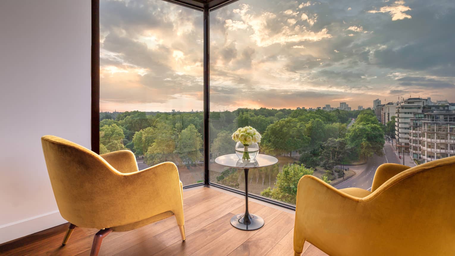 Two mustard-coloured club chairs and small round table on wood floor with views from large window