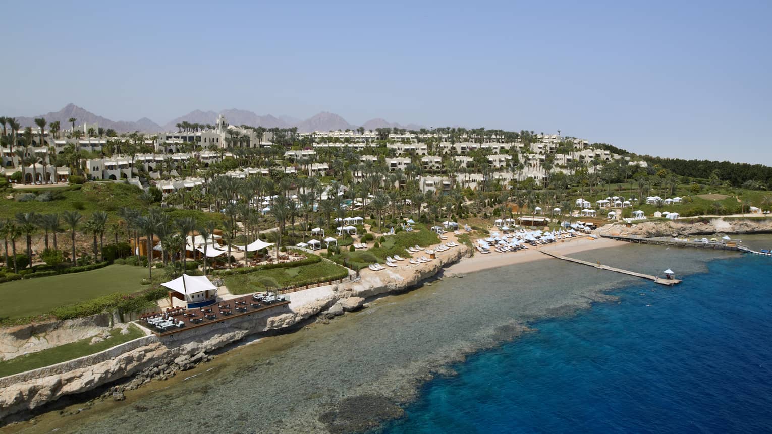 Aerial view of Four Seasons Resort Sharm El Sheikh along green hill, white sand beach
