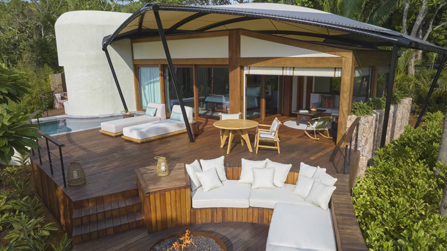 Luxury tent nestled within tropical forest, with outdoor lounge seating, fire pit and plunge pool