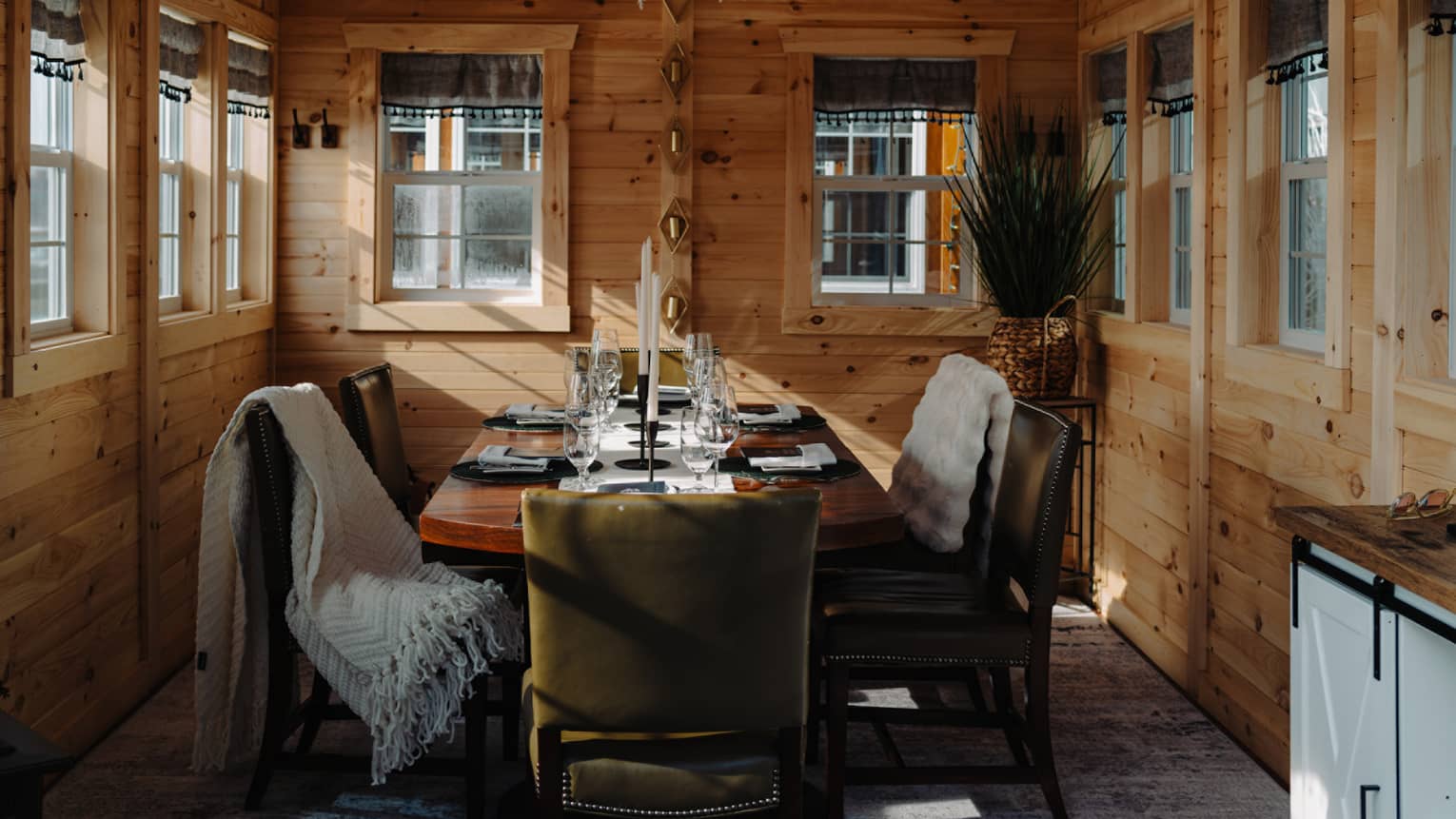 Entrance to a dining room with a wreath, and a dining table set with plates and glasses