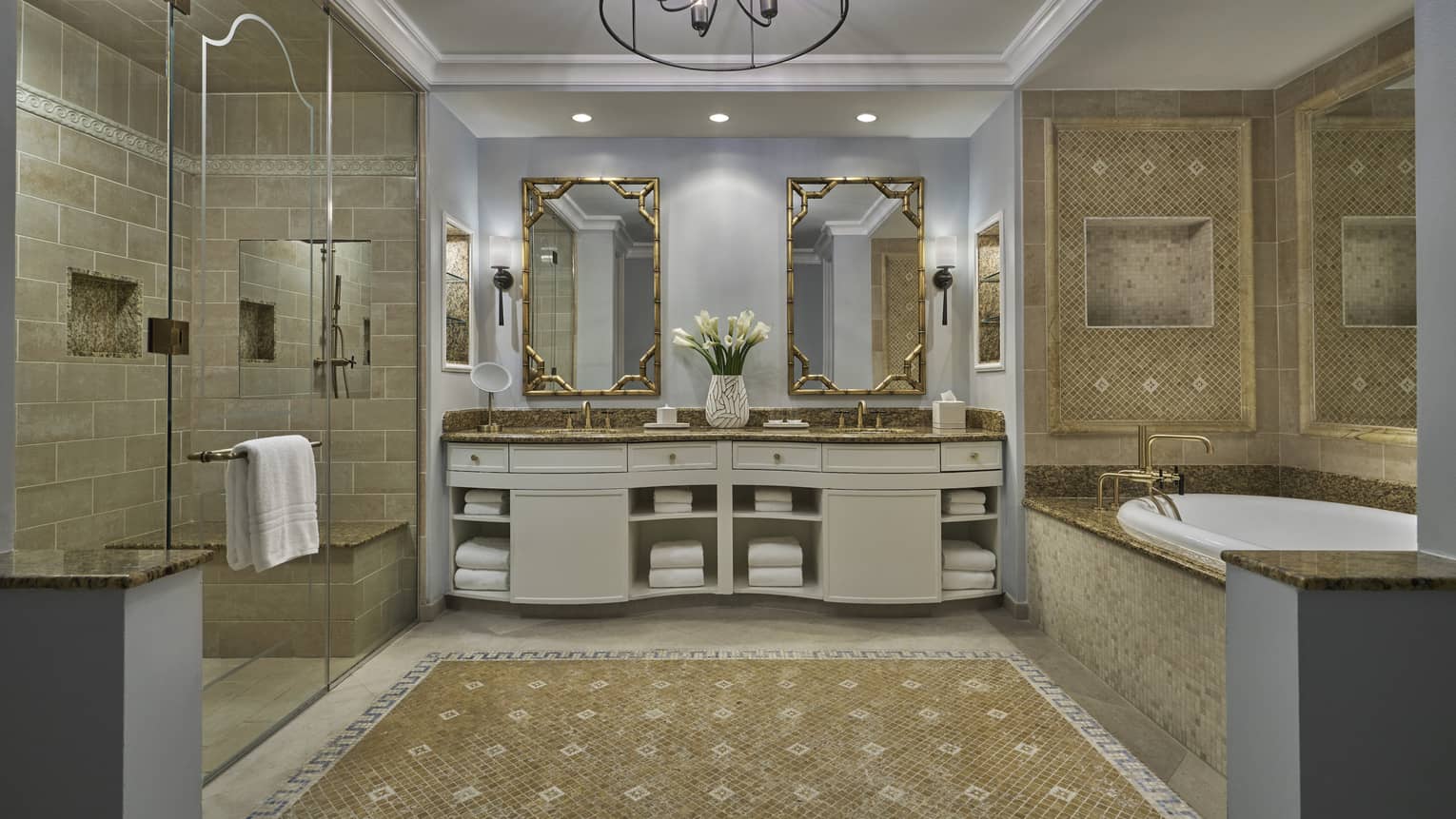 Luxury bathroom with dual sinks, gold-framed mirrors, a walk-in shower and a mosaic-tiled bathtub