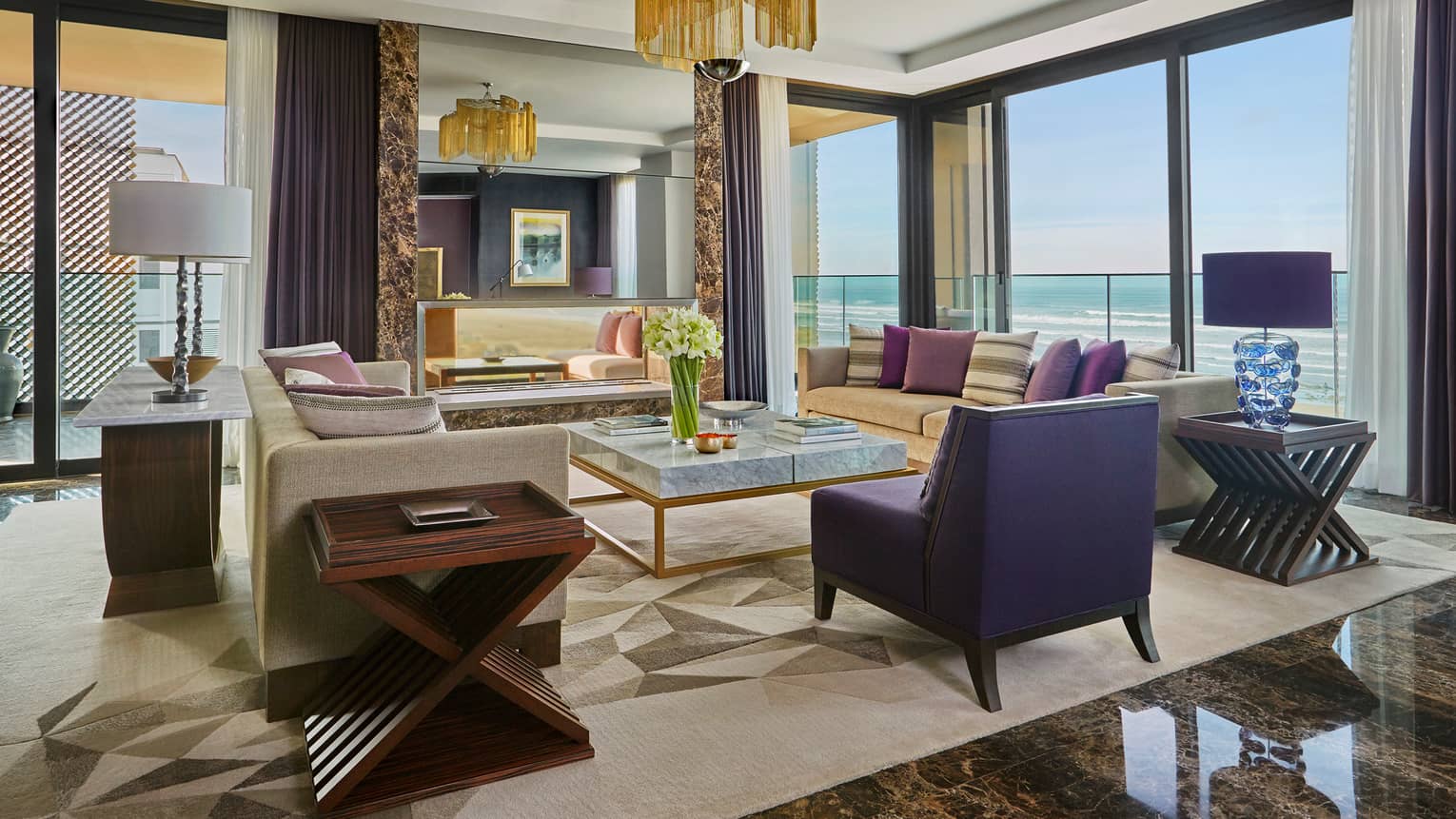 Royal Suite living room with modern sofas, tables, black marble floors, large mirror, chandelier