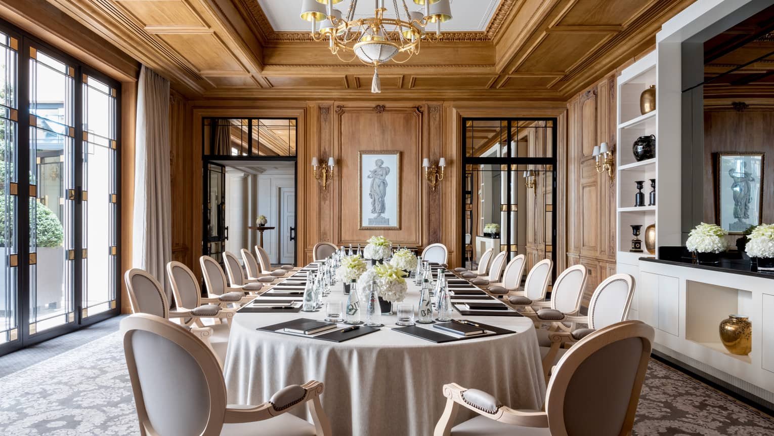 Long dining table, chairs in bright Napoléon meeting room with large windows