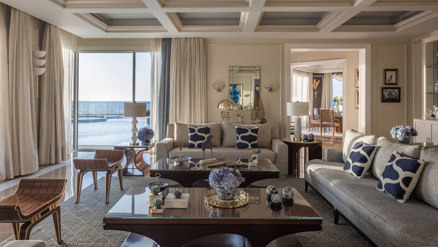 The Palace living area with cream and tan sofas, ergonomic cherry wood coffee tables, sliding glass doors to patio with pool