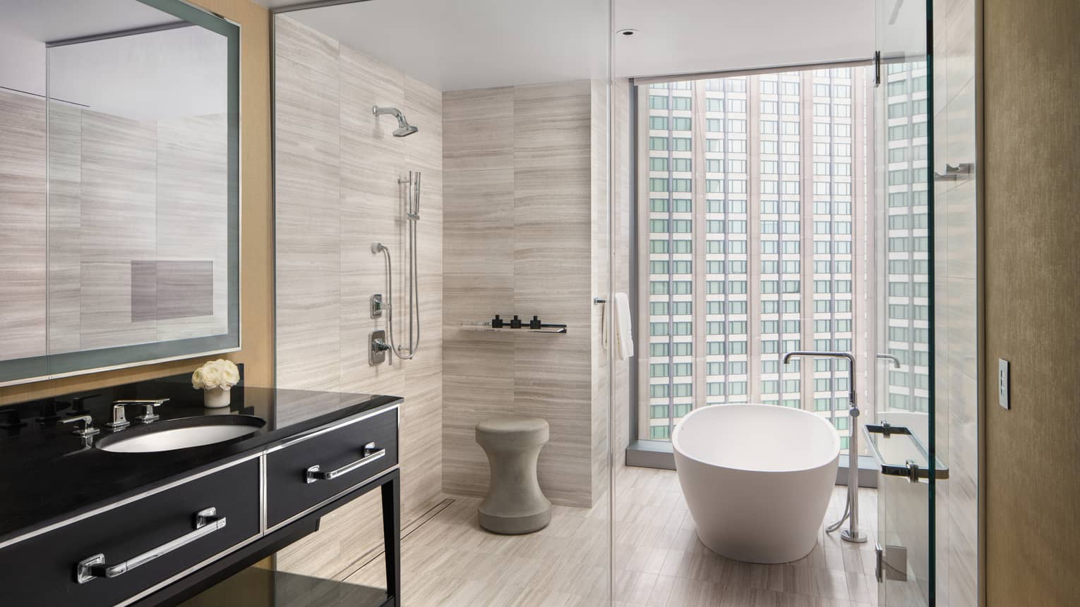 Premier room bathroom with black vanity and mirror, glass shower doors, large soaking tub