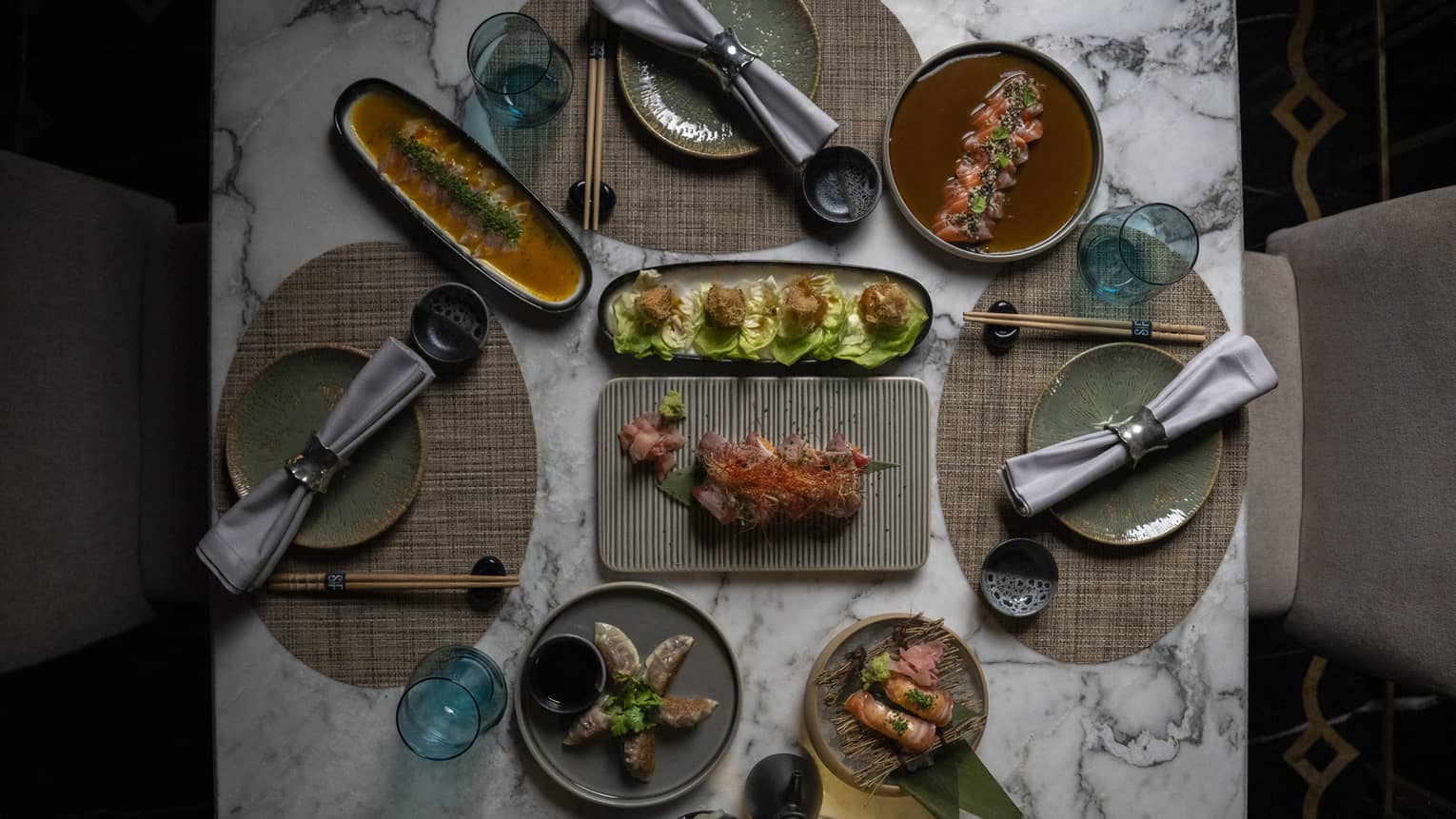 Overhead view of Jappanese Nikkei cuisine on a white marble table set for three