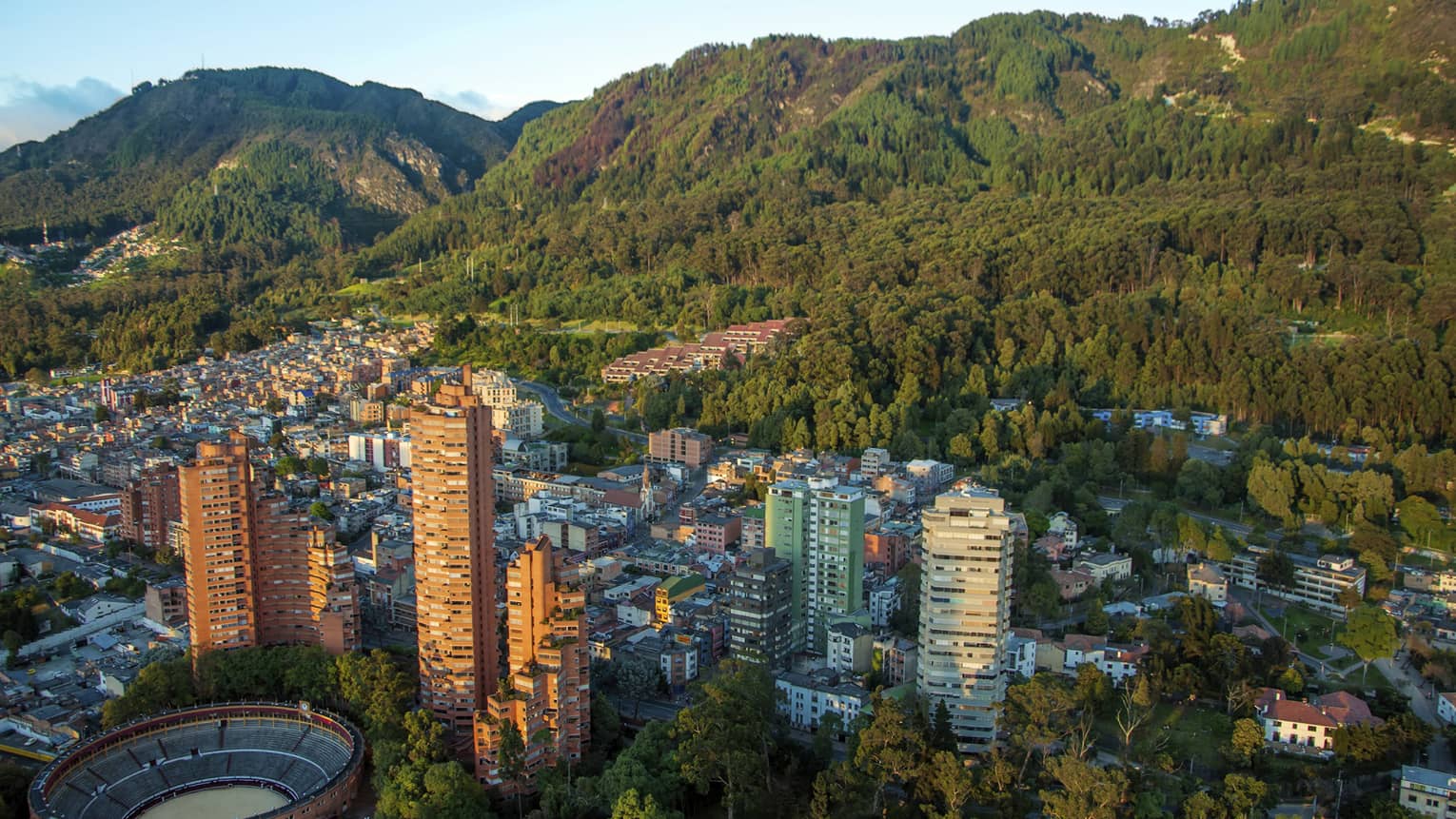 Aerial view of Bogota city high rises, houses and dome sports field on sunny day