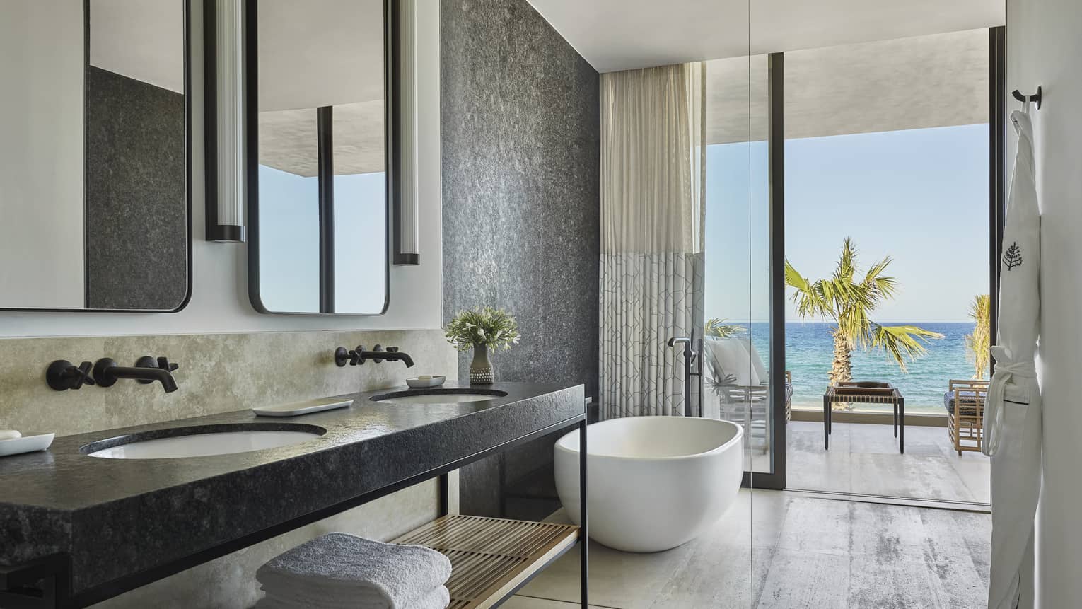 A bathroom with large sliding glass door, a sink with shelf, mirrors and bathtub.
