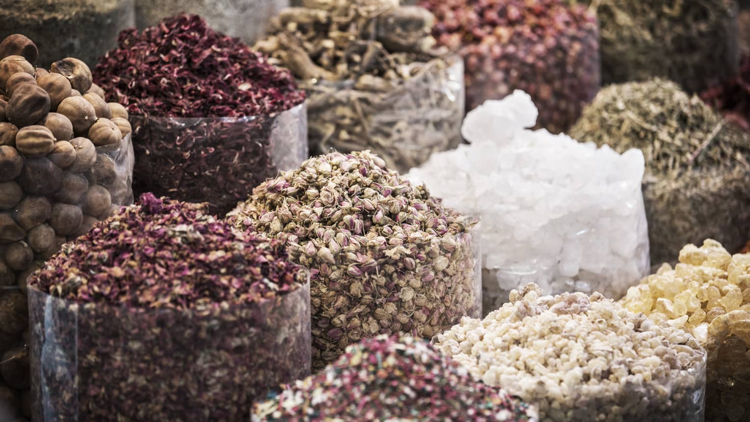 Clear cylindrical containers filled with dried Persian limes, rose buds, alum crystals and a myriad of other dried herbs. 